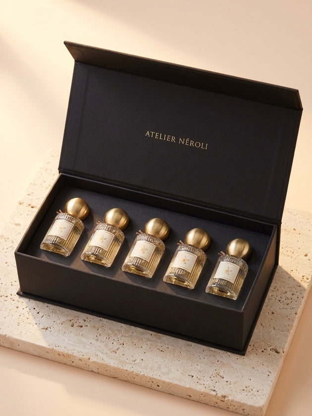 Coffret Découverte Atelier Néroli : cinq mini-flacons de 15 ml dans un coffret noir sur du travertin